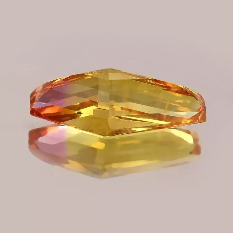 Faceted gemstone with a multicolored  Bi-Color Sapphire hue on a reflective surface