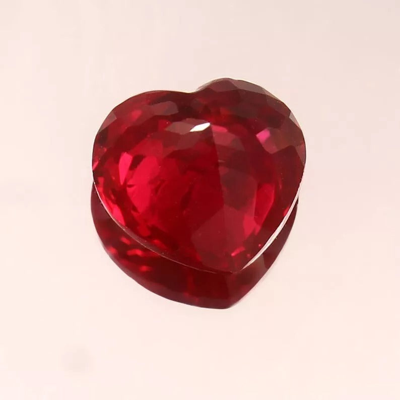 Heart-shaped Unheated Blood Red Mozambique Ruby gemstone on a light pink background