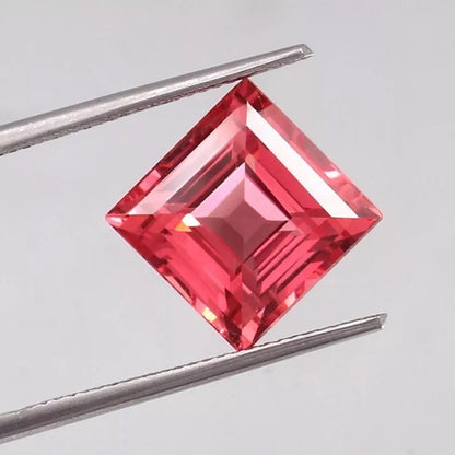 Square-cut Solomon Color Ceylon Padparadscha Sapphire gemstone held between tweezers on a light gray background