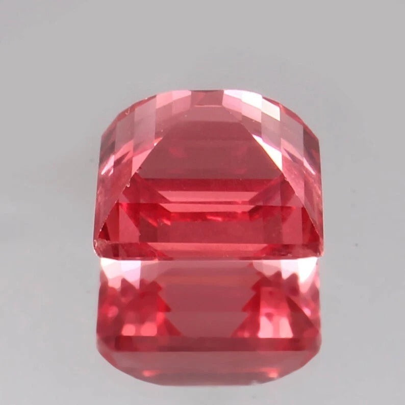 Faceted Solomon Color Ceylon Padparadscha Sapphire gemstone on a gray background