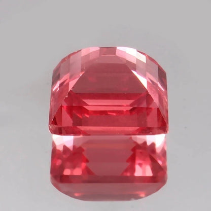 Faceted Solomon Color Ceylon Padparadscha Sapphire gemstone on a gray background