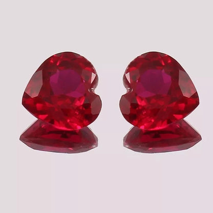 Pair Blood Red Mozambique Ruby heart-shaped objects on a light gray background