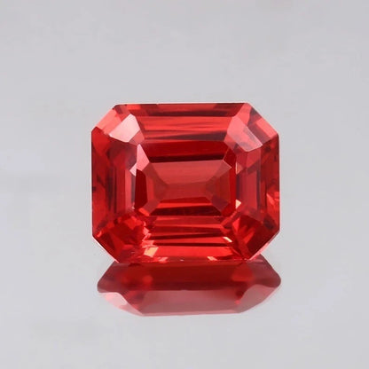 Solomon Color Padparadscha Sapphire gemstone with an emerald cut on a gray background