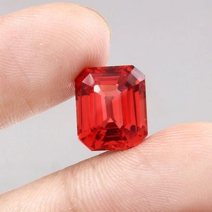 Solomon Color Padparadscha Sapphire gemstone held between fingers against a neutral background