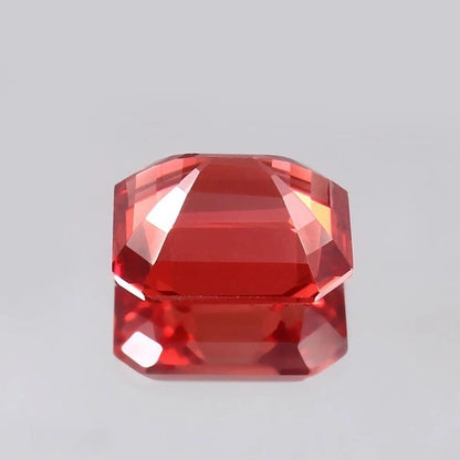 Faceted Solomon Color Padparadscha Sapphire gemstone on a gray background