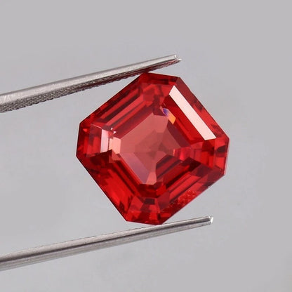 Solomon Padparadscha Sapphire gemstone held by tweezers against a gray background