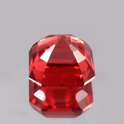 Faceted Solomon Padparadscha Sapphire gemstone on a gray background