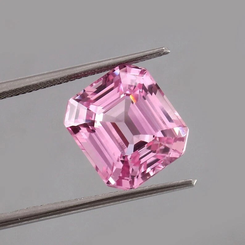 Pink Morganite Madagascar gemstone held between tweezers against a gray background