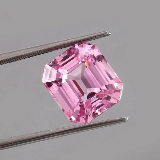 Pink Morganite Madagascar gemstone held between tweezers against a gray background