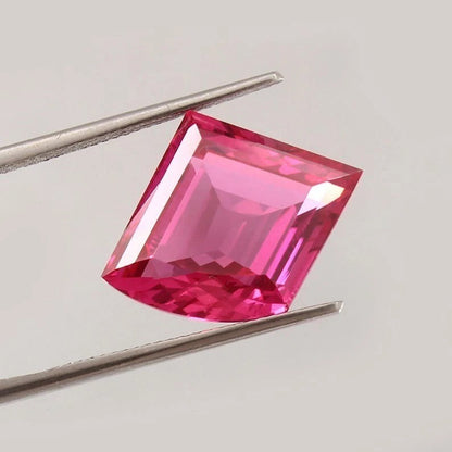 Pink Sapphire Fancy Cut gemstone held by tweezers on a light gray background