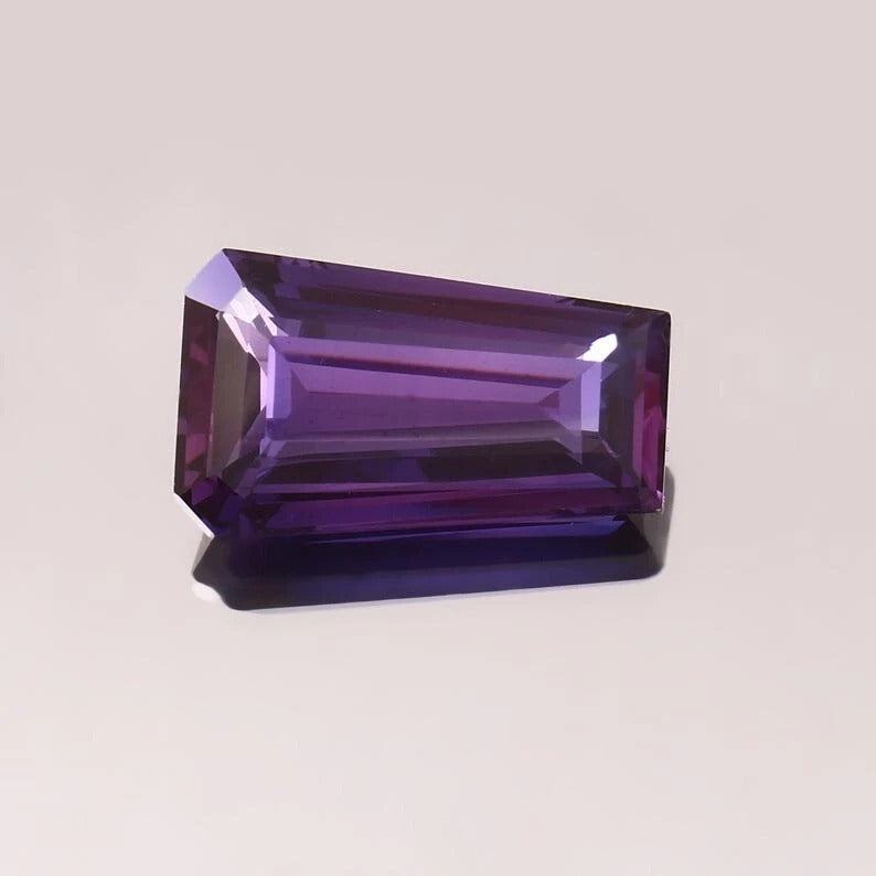 Fancy Purple Pink Taaffeite Sapphire gemstone on a light gray background