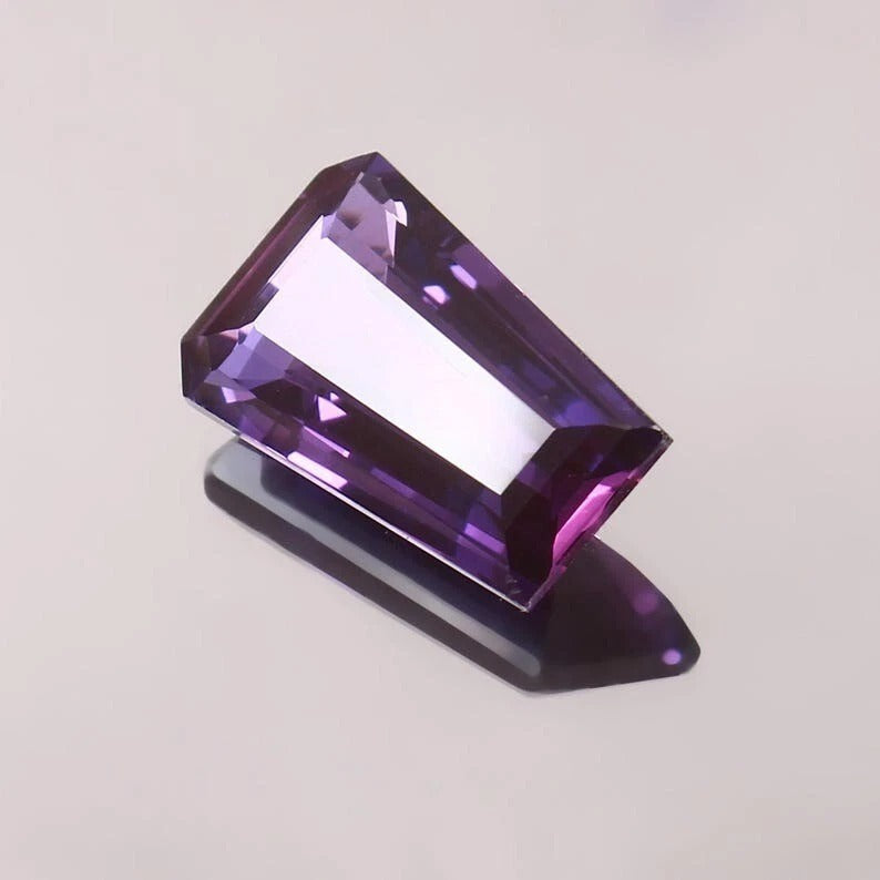 Faceted Purple Pink Taaffeite Sapphire gemstone on a light gray background