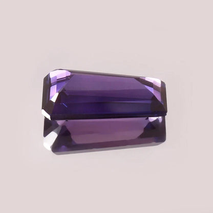 Faceted Purple Pink Taaffeite Sapphire gemstone on a light gray background