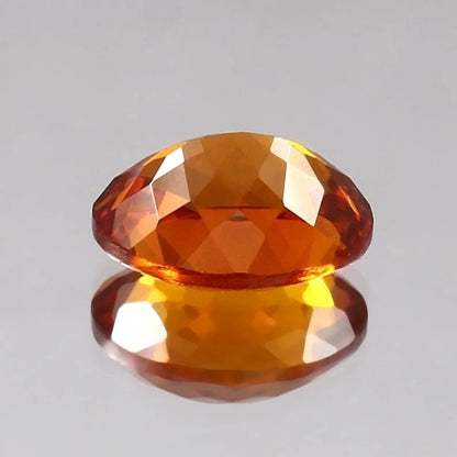 Faceted orange Sapphire gemstone on a gray background