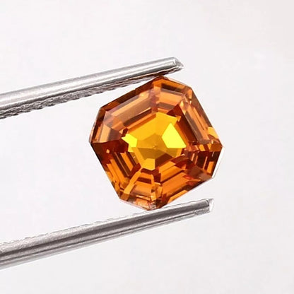 Ceylon Fanta Orange Sapphire Untreated gemstone held by tweezers on a white background