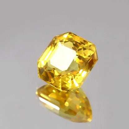 Faceted Yellow Sapphire Asscher gemstone on a gray background