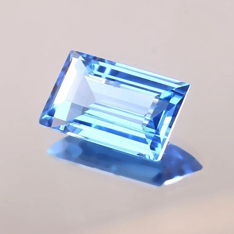 Brazilian Aquamarine Baguette Cut blue gemstone on a light gray background