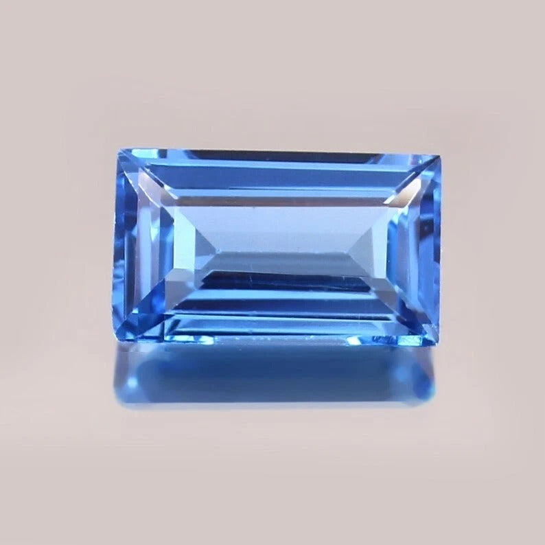 Brazilian Aquamarine Baguette Cut gemstone on a beige background