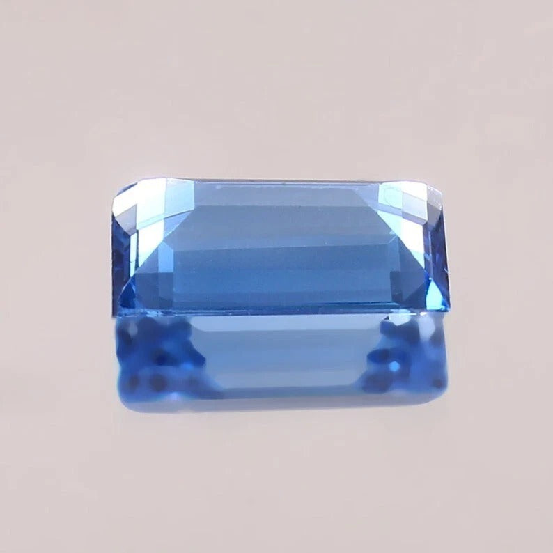 Brazilian Aquamarine Baguette Cut blue gemstone on a beige background