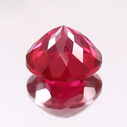 Faceted Rare Pigeon Red Ruby gemstone on a reflective surface with a white background