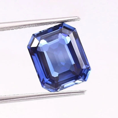 Blue Sapphire gemstone held by tweezers on a white background