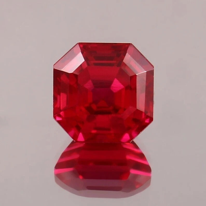 Faceted Pigeon Blood Ruby gemstone on a gray background