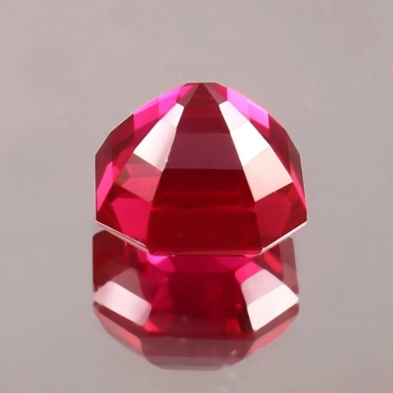 Faceted Pigeon Blood Ruby gemstone on a gray background