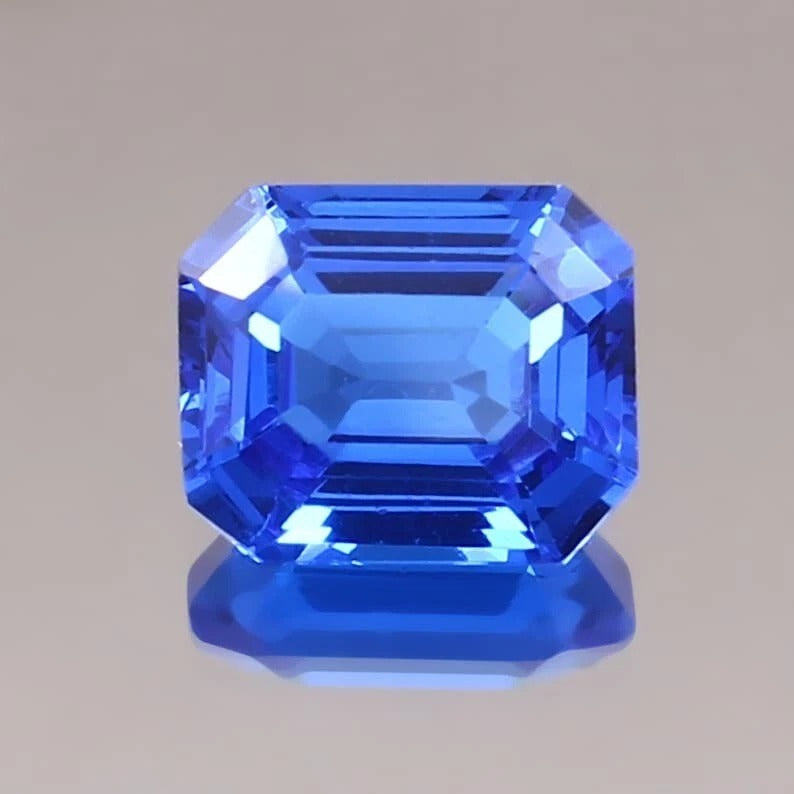 Faceted Cornflower Blue Sapphire gemstone on a gray background