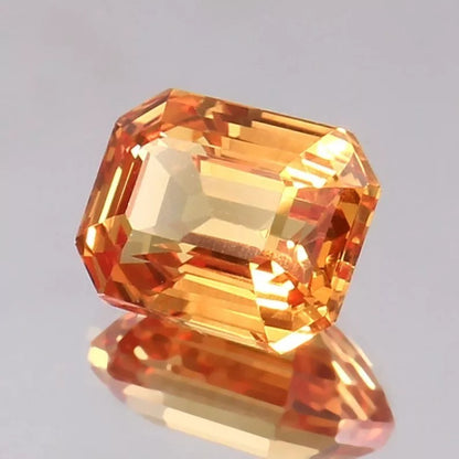 Faceted Peach Padparadscha gemstone on a gray background