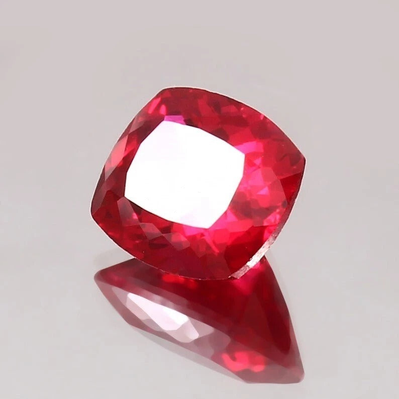 Faceted Pigeon Blood Ruby gemstone on a gray background