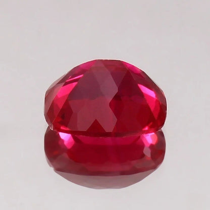 Faceted Pigeon Blood Ruby gemstone on a light gray background