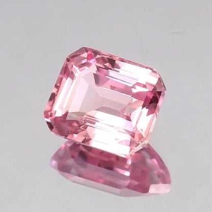 Padparadscha Sapphire gemstone on a gray background
