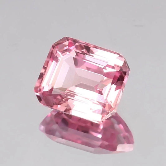 Padparadscha Sapphire gemstone on a gray background