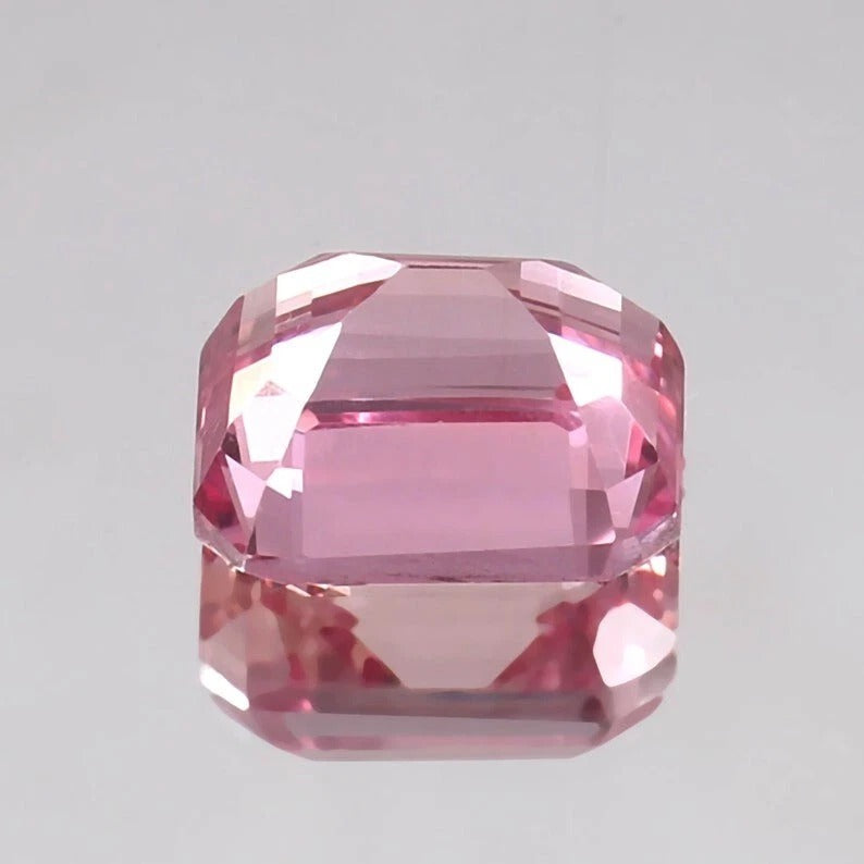 Padparadscha Sapphire gemstone on a gray background