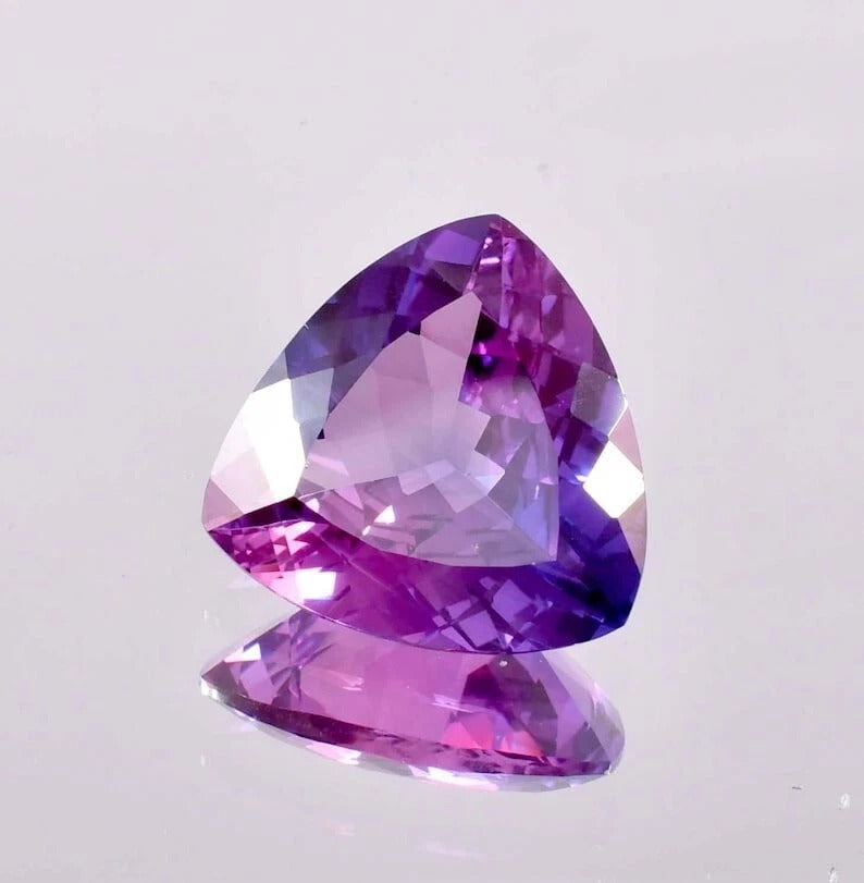 Heart-shaped Bi-Color Purple Sapphire gemstone on a light gray background