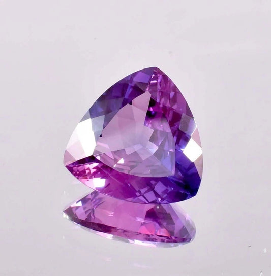 Heart-shaped Bi-Color Purple Sapphire gemstone on a light gray background