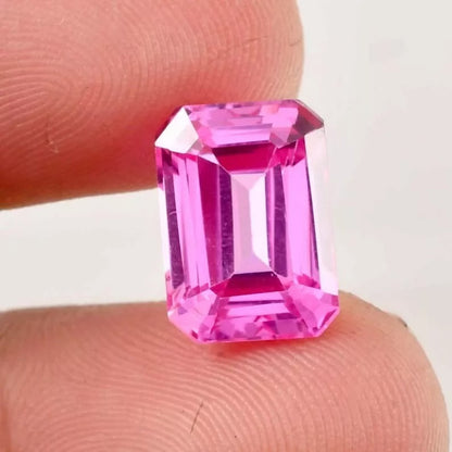 Pink Ceylon Sapphire gemstone held between two fingers against a white background