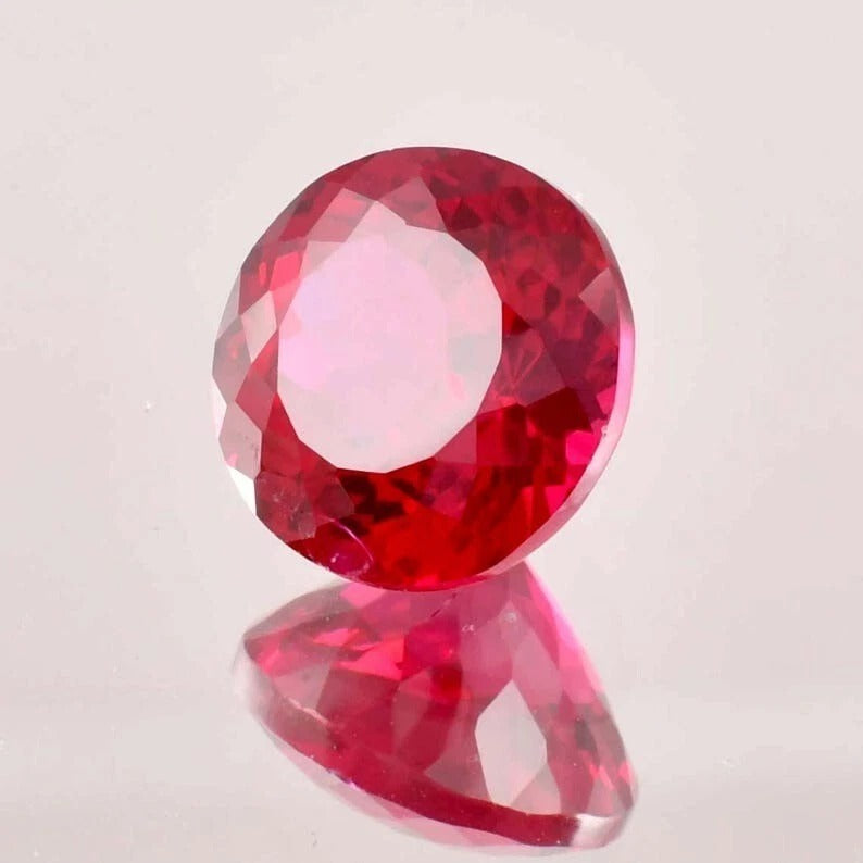 Faceted ruby red gemstone on a light gray background