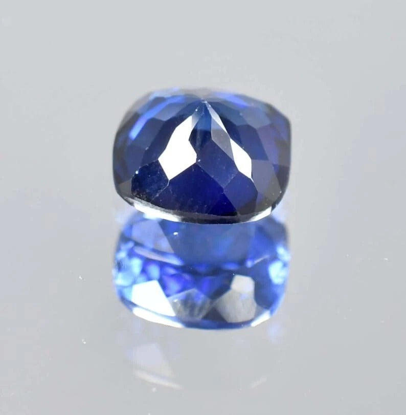 Blue Sapphire cushion gemstone on a light gray background