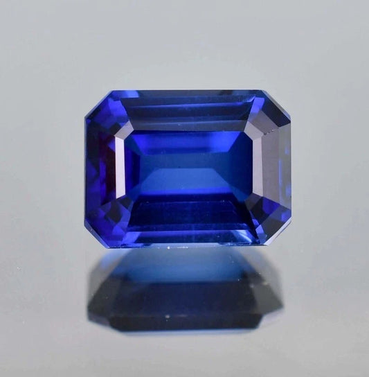 Faceted Royal Blue Sapphire gemstone on a light gray background