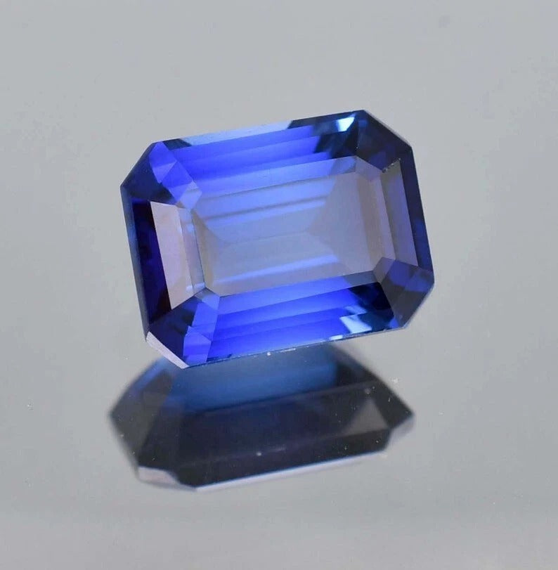 Faceted Royal Blue Sapphire gemstone on a gray background