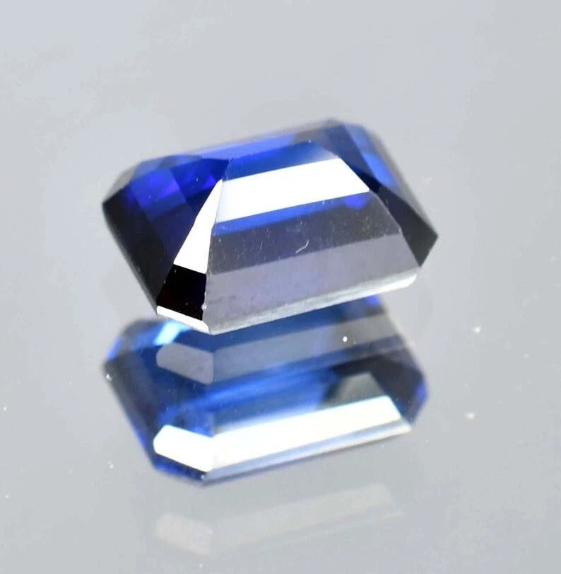 Faceted Royal Blue Sapphire gemstone on a light gray background