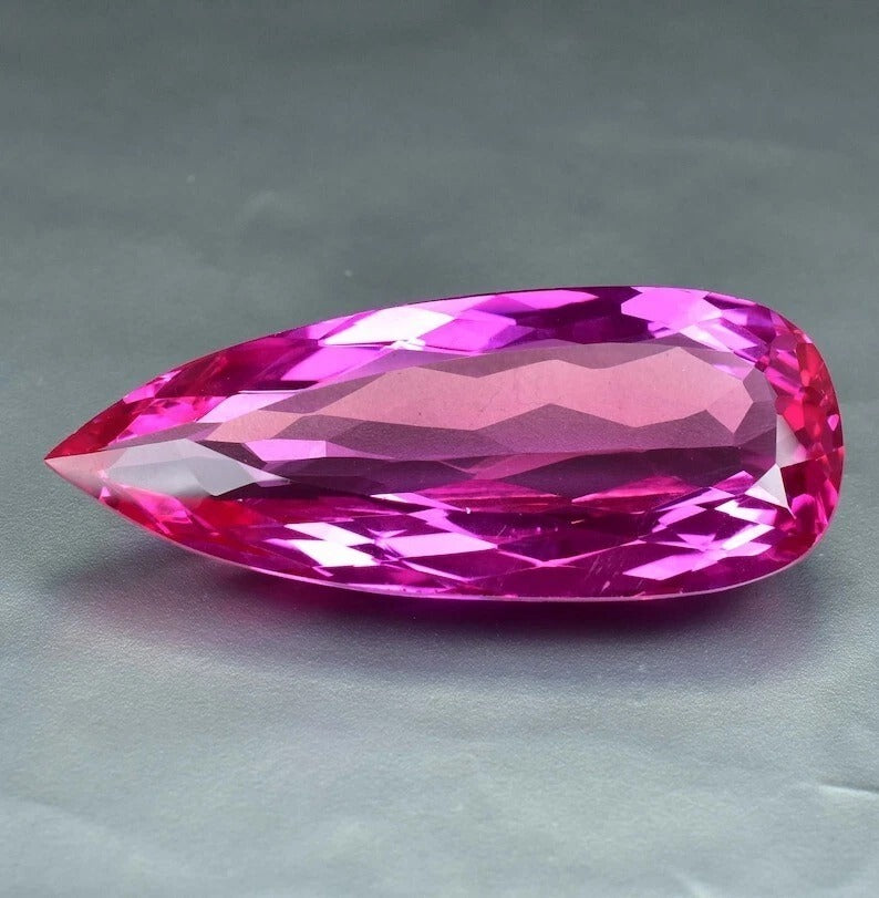 Faceted Royal Pink Ceylon Sapphire gemstone on a gray background