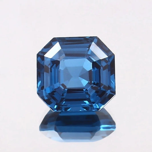Faceted blue Tourmaline gemstone on a light gray background