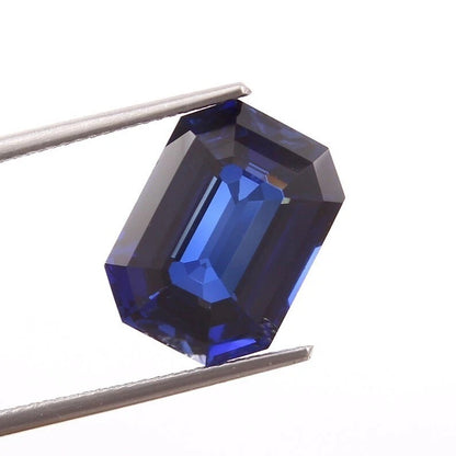 Ceylon Blue Sapphire gemstone held between tweezers on a white background