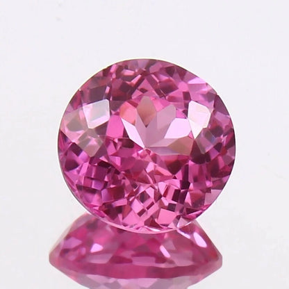 Pink Sapphire gemstone on a reflective surface with a light purple background