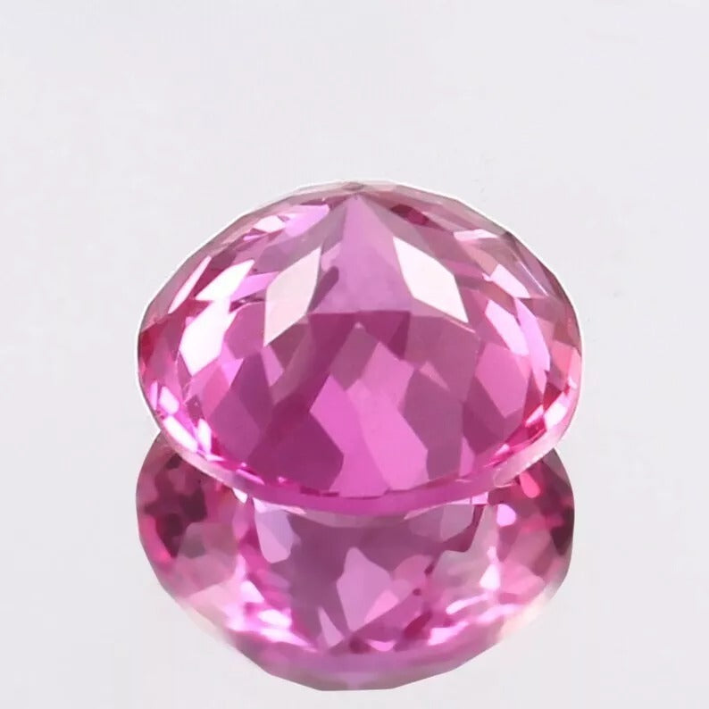 Faceted Pink Sapphire gemstone on a light gray background