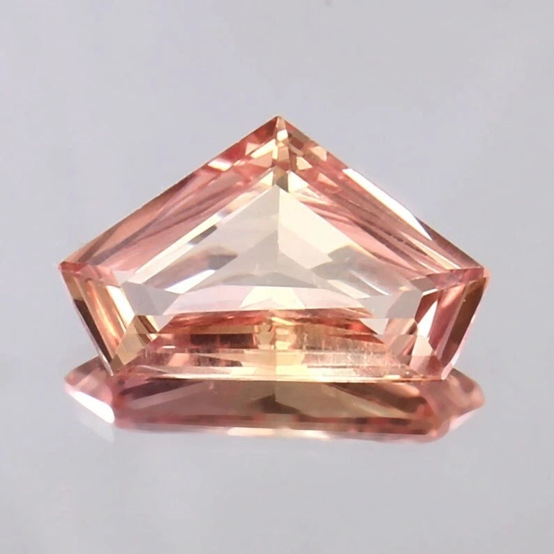 Padparadscha Sapphire gemstone on a light gray background