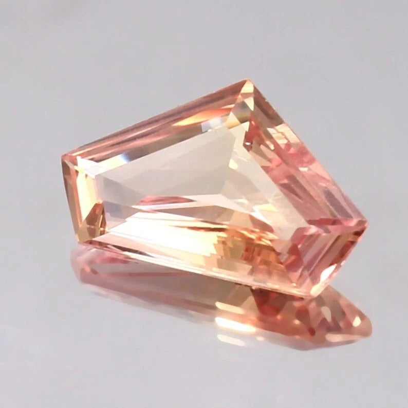 Rectangular Padparadscha Sapphire gemstone on a gray background