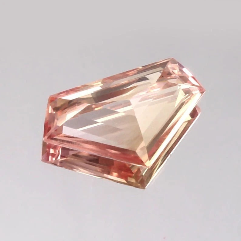 Rectangular Padparadscha Sapphire gemstone on a gray background